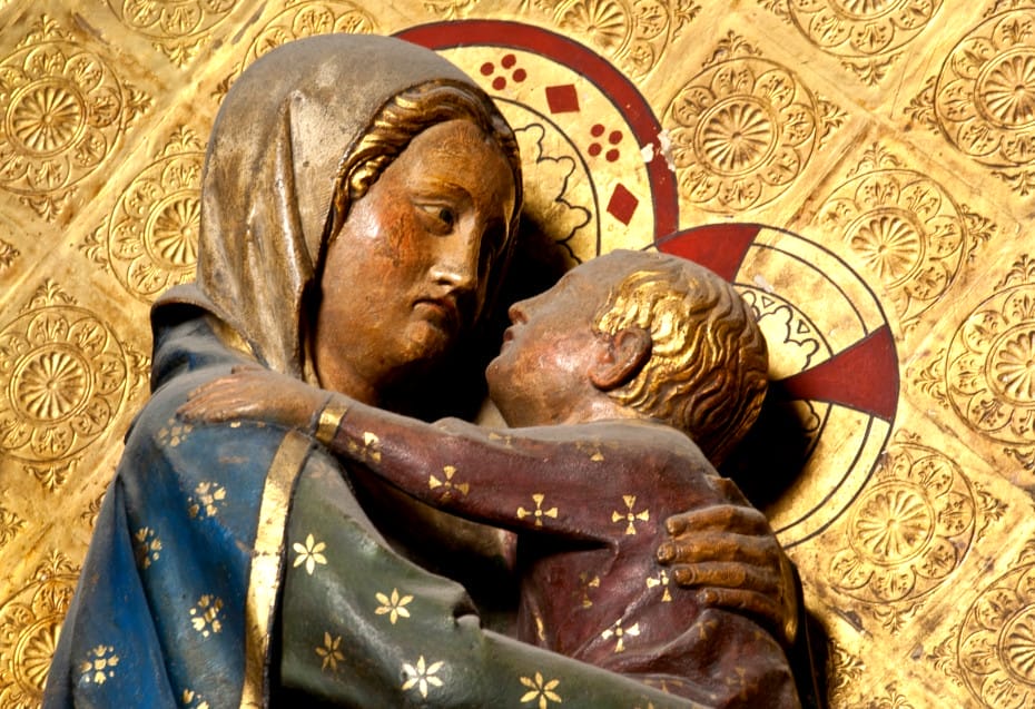 Gros plan sur la Vierge portant l'enfant dans ses bras sur le tour de choeur, mur de gravures dorées