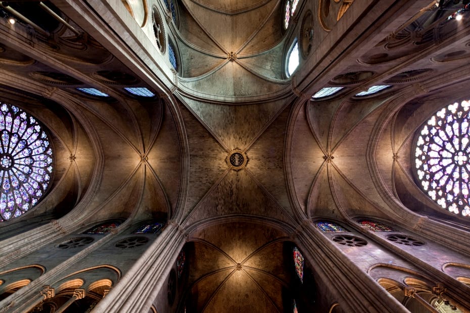 Photographie en contre-plongée de l'intérieur de la cathédrale, les plafonds symétriques avec des vitraux aux extrémitées